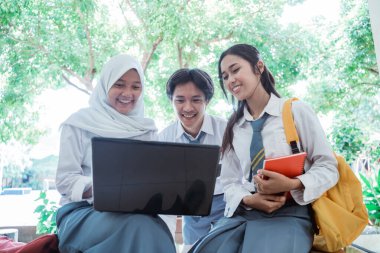 Lise öğrencilerinin dizüstü bilgisayarlarıyla, kitap taşırken ve çanta taşırken