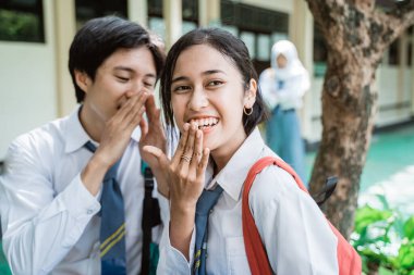 Bir oğlan, okul bahçesinde kız arkadaşıyla otururken liseli üniformalı bir kıza gülümsemesini fısıldadı.