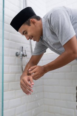 Genç Müslüman adam evde namaz kılmadan önce abdest alıyor.