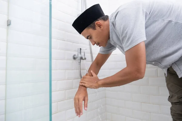 Young Muslim man perform ablution wudhu before prayer at home