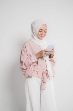 Genç Müslüman kadın cep telefonundan mesaj atarken gülümsüyor