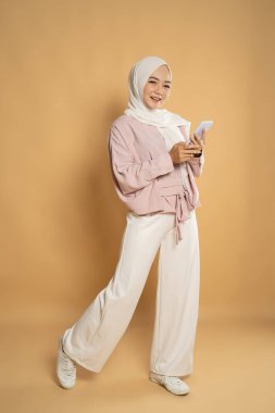 Müslüman kadın cep telefonundan mesaj atarken gülümsüyor