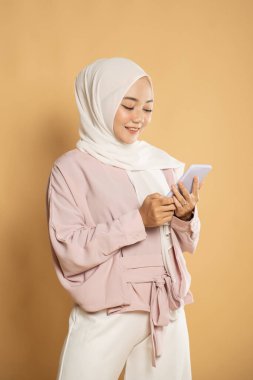 Müslüman kadın cep telefonundan mesaj atarken gülümsüyor