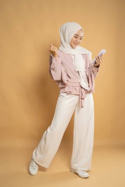 Genç Müslüman kadın cep telefonundan mesaj atarken heyecanlanıyor