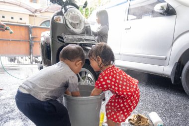 Asyalı çocuk evde motosiklet scooter 'ı yıkıyor.