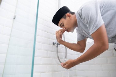 Genç Müslüman adam evde namaz kılmadan önce abdest alıyor.