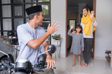 Müslüman bir adam motosikletle giderken ailesini evde bırakıyor.