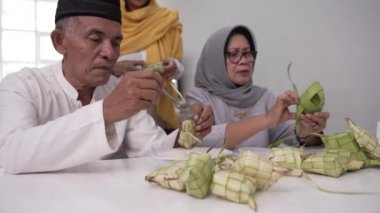 Müslüman çift evde bayram için ketupat yapıyor.