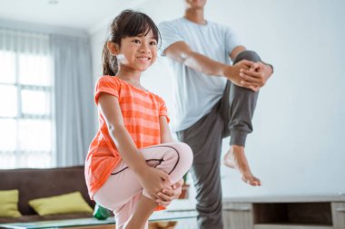 Baba ve kızı evde birlikte egzersiz yapıyorlar.