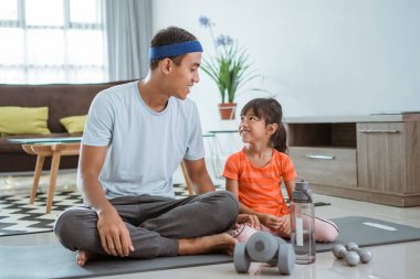 Baba ve kızı evde birlikte egzersiz yapıyorlar.