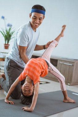 Baba kızına evde esneme hareketleri için yardım ediyor.