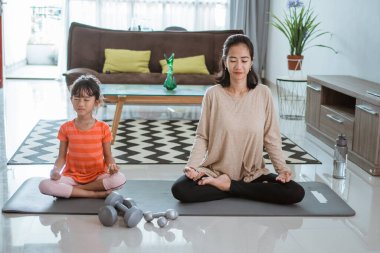 Anne kızıyla birlikte evde yoga egzersizi yapıyor.