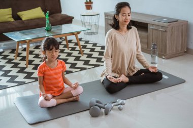 Anne kızıyla birlikte evde yoga egzersizi yapıyor.