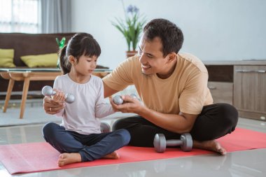 Çocuk ve babası evde ağırlık kaldırıyorlar.