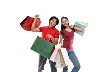 Mutlu genç Asyalı çift mutlu bir ifadeyle el kaldırırken bir sürü renkli alışveriş çantası getiriyor.