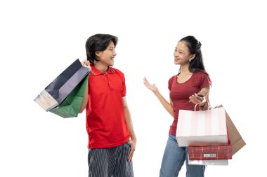 Asyalı genç erkekler ve kadınlar alışveriş torbaları tutarken birbirlerine bakıyorlar.