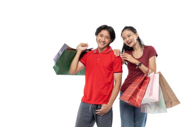 Asyalı genç erkekler ve kadınlar ellerinde alışveriş torbalarıyla kameraya bakarken poz veriyorlar.