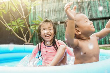İki küçük çocuk güneşli bir günde açık havuzda oynuyorlar..
