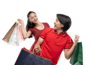 Mutlu genç Asyalı çift bir sürü renkli alışveriş çantası taşıyor, birbirlerine bakıyorlar, mutlu bir ifade.