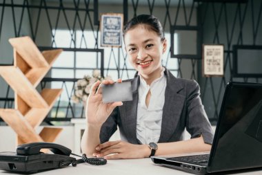 Ofiste banka kartı tutan gülümseyen genç bir kızın portresi.