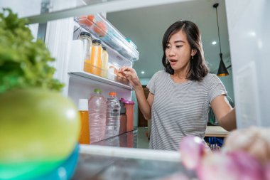 Güzel ev hanımı yemek hazırlıyor. Dolaptan biraz malzeme alıyor.