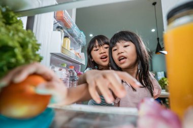 Asyalı kız buzdolabının kapısını açtı ve bir şişe meyve suyu içti.