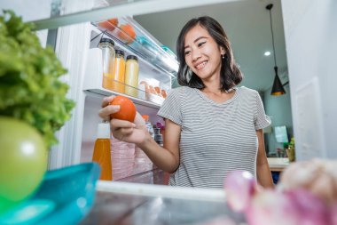 Güzel ev hanımı yemek hazırlıyor. Dolaptan biraz malzeme alıyor.