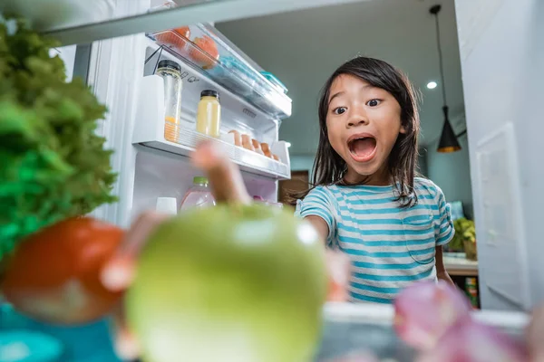 asian girl open fridge door drinking a bottle of juice