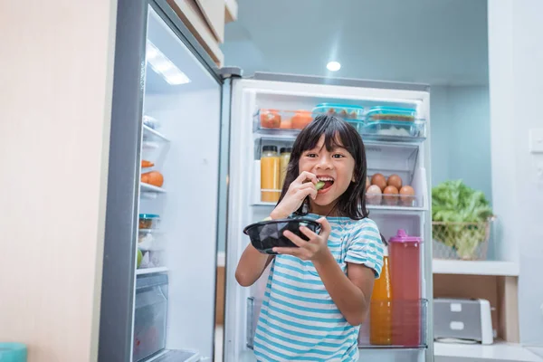 asian girl open fridge door drinking a bottle of juice