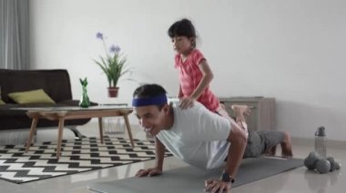 Baba ve çocuk birlikte egzersiz yapıyor. Evde yapılan sağlıklı aile çalışmalarının portresi.