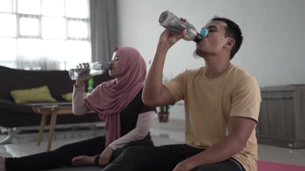 Man and woman exercising together at home drinking water — Stock Video