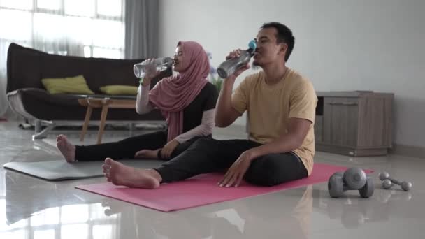 Uomo e donna che si esercitano insieme a casa acqua potabile — Video Stock
