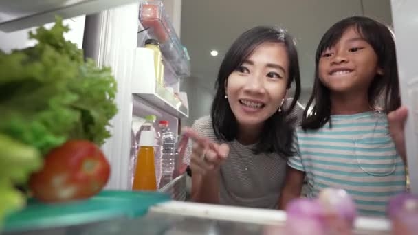 Matka i jej córka mają czas przekąski razem w kuchni otworzyć lodówkę — Wideo stockowe