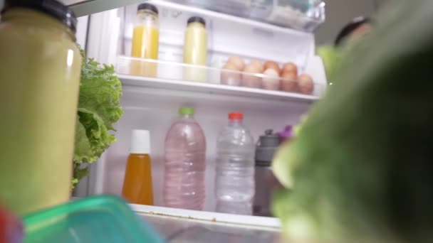 Wife preparing for dinner taking some ingredient from the fridge. shoot from inside — Stock Video