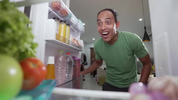 Excited starving young asian man opening the fridge door — Stock Video