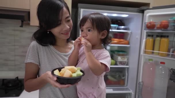 幼い赤ちゃんを連れて一緒に果物を食べる母親 — ストック動画