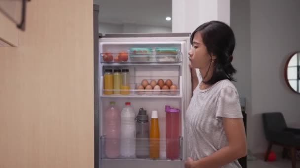 Hungrige junge Asiatinnen essen Obst aus dem Kühlschrank — Stockvideo