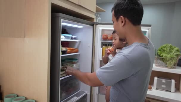 Vater und Sohn öffnen Kühlschrank zu Hause auf der Suche nach Essen — Stockvideo