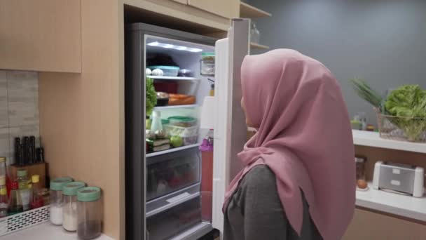 Muslimsk kvinna öppna kylskåpsdörren och gör sig redo att laga mat till middag — Stockvideo