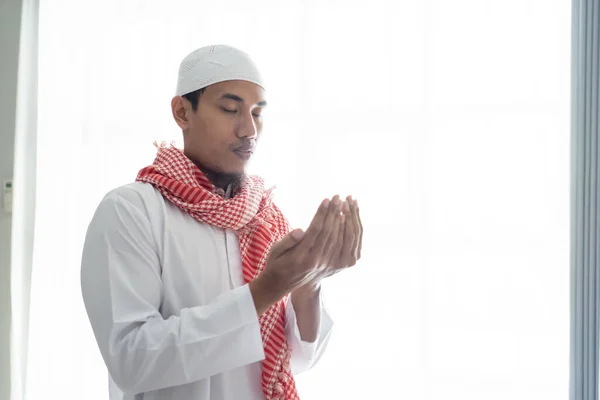 Muslimischer Mann betet mit der Hand gegen weißes Fenster — Stockfoto