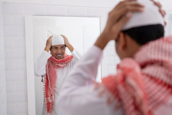 Muslim pria melihat cermin dan berpakaian topi islamic atau topi — Stok Foto