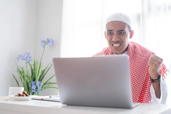 怒ったイスラム教徒の男性がノートパソコンの画面を見て — ストック写真
