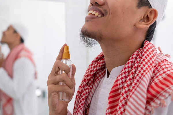 Pria muslim berpakaian dan menerapkan parfum ke tubuhnya — Stok Foto