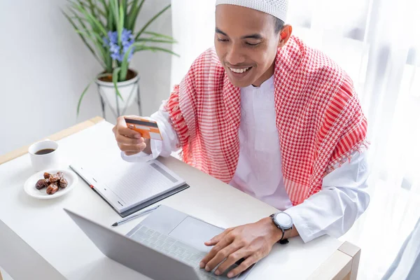 ムスリムアジア人男性がオンラインショップでの支払いにクレジットカードを使うと — ストック写真