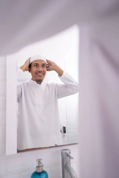 Muslim man looking at mirror and get dressed wearing islamic hat or cap — Stock Photo, Image