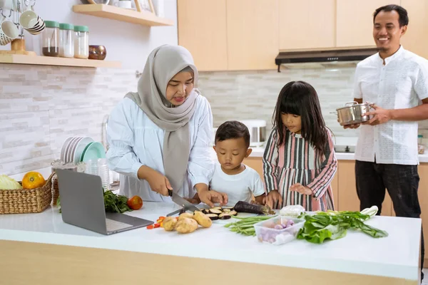 Muslim keluarga dengan dua anak memasak bersama-sama di rumah mempersiapkan untuk makan malam iftar — Stok Foto
