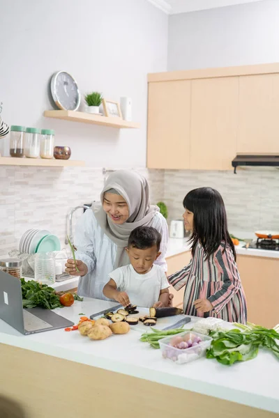 Wanita asia yang cantik dengan anak perempuan dan anak memasak makan malam selama bulan Ramadan — Stok Foto