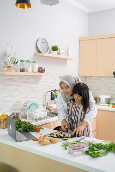 Wanita muslim asia dengan anaknya memasak bersama di dapur selama bulan Ramadan — Stok Foto
