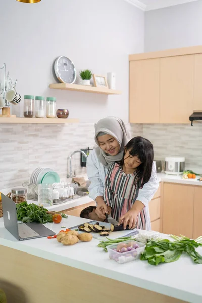 Memiliki wanita menyenangkan dengan hijab dan anak mempersiapkan makan malam bersama-sama — Stok Foto