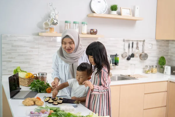 Wanita asia yang cantik dengan anak perempuan dan anak memasak makan malam selama bulan Ramadan — Stok Foto
